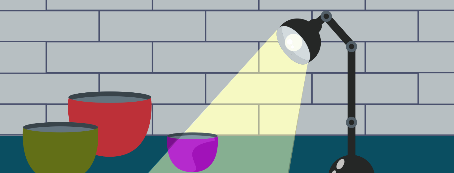 A desk light shines down on a dark kitchen counter.