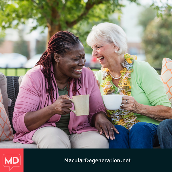 A clear vision of two women sit outside drinking coffee and laughing with one another