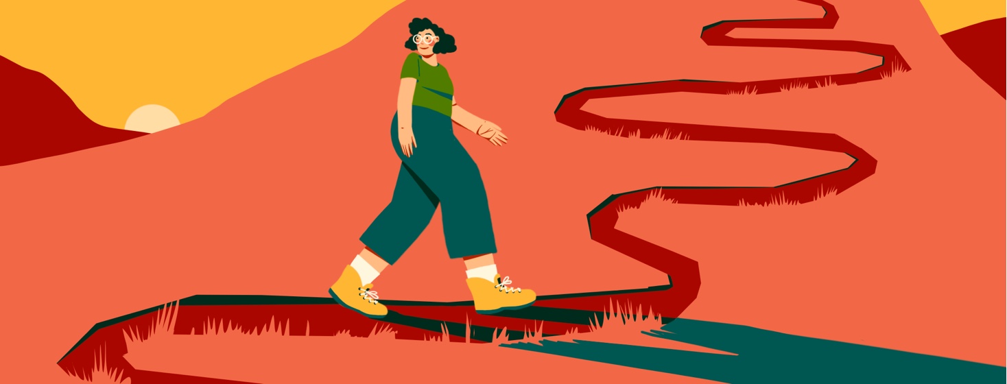 A woman is walking up a winding path, smiling and looking over her shoulder.