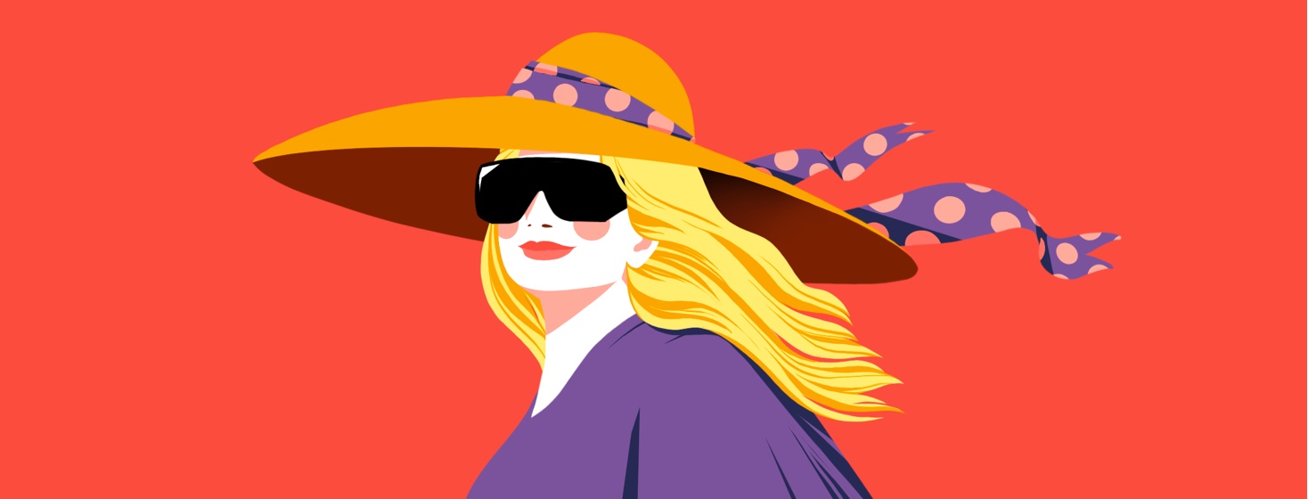 A smiling woman in a bright space is wearing a large sun hat with a ribbon blowing in the wind, and large, dark cataract sunglasses.