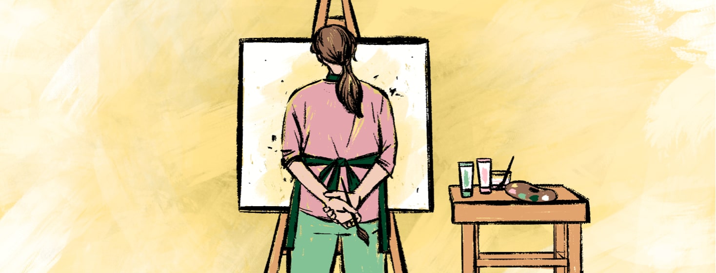 alt=A woman stands in front of a painted canvas on an easel next to a table with paints and a palette.