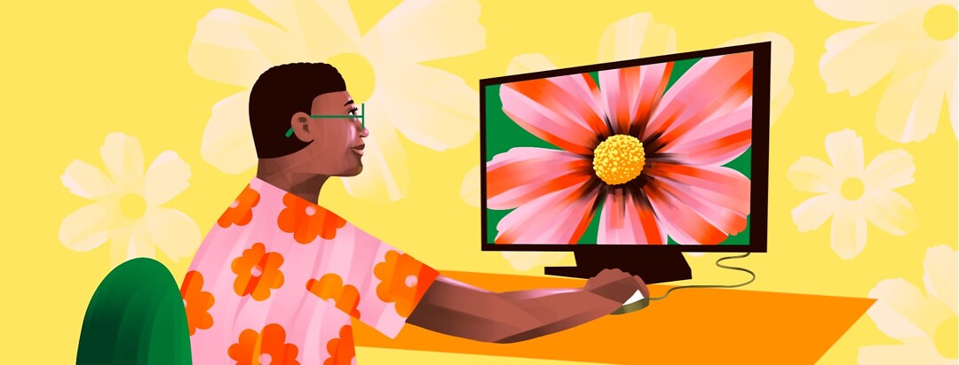 alt=a woman uses a computer with a large screen displaying a flower close-up