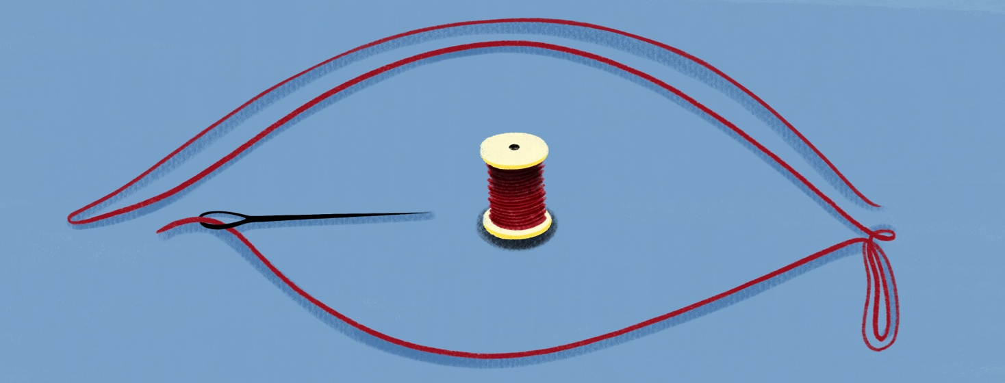 A spool of thread and a threaded needle are laid out to look like a crying eye