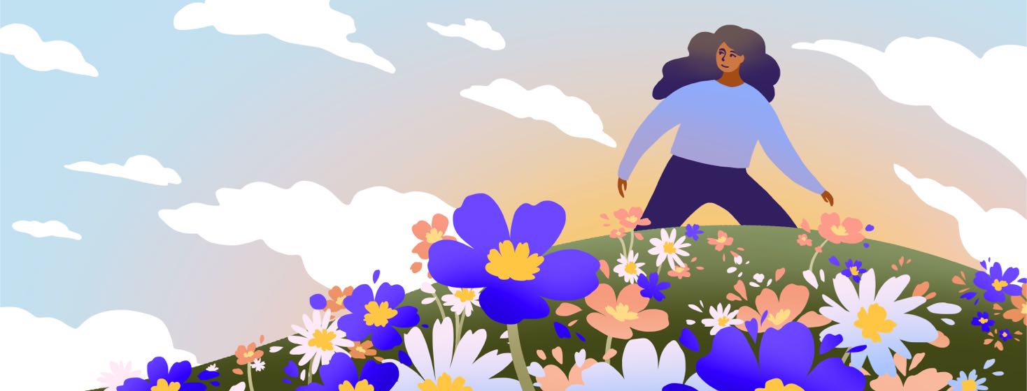 A woman walks over a hill covered in flowers with a smile on her face.